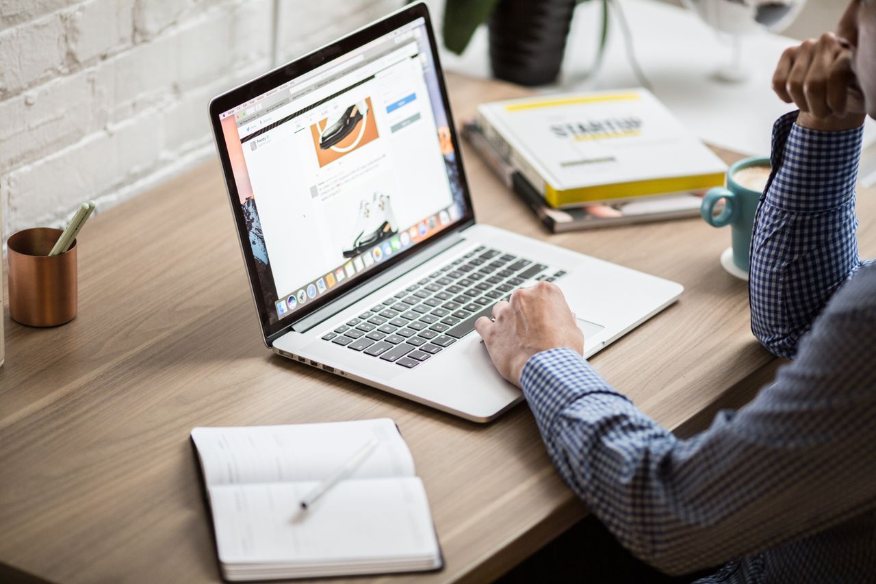 Adult working on a laptop in a modern office setting, illustrating productivity and concentration.